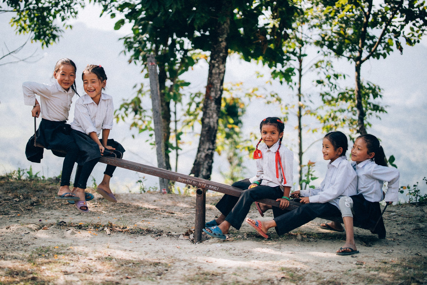 Children playing on a seesaw near a school supported in Nepal