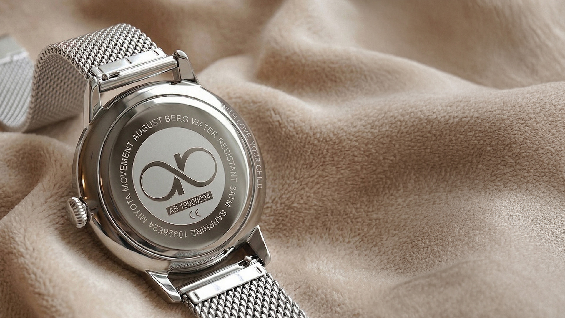 August Berg watch caseback engraved With love, your child, resting on a beige cloth